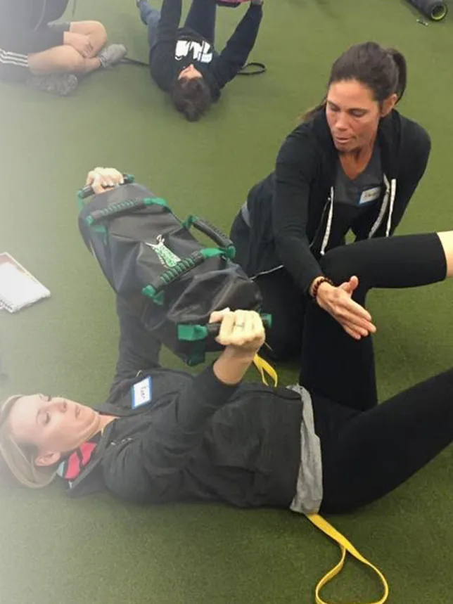 A DVRT instructor coaching a student through a floor drill during a certification